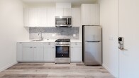 Located at 1530 Cassil Place in the heart of Hollywood, Los Angeles, this modern single-floor unit offers a clean, contemporary aesthetic throughout. Light-toned wood-style flooring runs seamlessly across all living areas, complementing the crisp white walls and recessed lighting that create a bright, airy atmosphere.

The kitchen is thoughtfully designed with flat-front cabinetry in a soft white finish, a grey subway tile backsplash, white quartz countertops, and a full suite of stainless steel appliances including a gas range, over-the-range microwave, and refrigerator. A keypad-secured entry door opens directly adjacent to the kitchen, offering a convenient and secure access point.

The bedrooms are well-proportioned and filled with natural light. One features a large sliding glass door that opens to a balcony with sweeping views of the surrounding Hollywood neighborhood and hills beyond, while the other benefits from a bright window bringing in additional daylight.

The bathroom stands out as a design highlight, featuring a walk-in glass-enclosed shower clad in richly toned cobalt blue brick-style tiles, paired with neutral stone-look floor tiles — a bold contrast that adds character to the otherwise minimal palette. The overall ambiance of the unit is fresh, modern, and move-in ready.