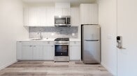 Located at 1530 Cassil Place in the heart of Hollywood, Los Angeles, this modern single-floor unit offers a clean, contemporary aesthetic throughout. Light-toned wood-style flooring runs seamlessly across all living areas, complementing the crisp white walls and recessed lighting that create a bright, airy atmosphere.

The kitchen is thoughtfully designed with flat-front cabinetry in a soft white finish, a grey subway tile backsplash, white quartz countertops, and a full suite of stainless steel appliances including a gas range, over-the-range microwave, and refrigerator. A keypad-secured entry door opens directly adjacent to the kitchen, offering a convenient and secure access point.

The bedrooms are well-proportioned and filled with natural light. One features a large sliding glass door that opens to a balcony with sweeping views of the surrounding Hollywood neighborhood and hills beyond, while the other benefits from a bright window bringing in additional daylight.

The bathroom stands out as a design highlight, featuring a walk-in glass-enclosed shower clad in richly toned cobalt blue brick-style tiles, paired with neutral stone-look floor tiles — a bold contrast that adds character to the otherwise minimal palette. The overall ambiance of the unit is fresh, modern, and move-in ready.
