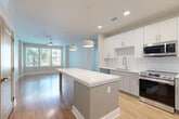 Located at 1464 Laurel Sound Lane in Sanford, FL, this well-appointed 2-bedroom, 2-bathroom single-story home offers a thoughtfully designed open-concept layout. The combined living, dining, and kitchen area serves as the heart of the home, featuring warm wood-look flooring, recessed lighting, and ceiling fans throughout. The kitchen is a standout, outfitted with crisp white shaker cabinetry, a classic subway tile backsplash, quartz countertops, stainless steel appliances including a French door refrigerator, and a generous center island with pendant lighting — ideal for both cooking and casual dining. Natural light flows in through large windows, offering views of lush greenery outside. The bedrooms are comfortably sized, with the primary bedroom featuring plush carpeting, ample natural light, and access to a well-organized walk-in closet with wire shelving systems. The bathrooms are finished with marble-style tile surrounds, wood-look flooring, white vanities with dark countertops, and backlit mirrors. Additional highlights include multiple closets, a dedicated laundry area, and a clean, neutral color palette that lends a bright, modern ambiance throughout the home.