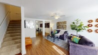 This two-story residence in Tallahassee, FL offers a well-organized layout across two levels. The main living area is anchored by warm hardwood flooring that extends throughout, complemented by white walls and a textured ceiling. A ceiling fan provides comfort overhead, while natural light streams in through multiple windows, illuminating the open-concept space. The living room flows seamlessly into a dedicated dining area, visible through a structural column passthrough, creating a connected yet defined layout.

The kitchen is equipped with white cabinetry, dark countertops, a coil-burner electric range with overhead ventilation, and ample storage. Two full bathrooms are present in the home — one featuring tile flooring, a vanity with dark countertop, and a tub-shower combination, and the other similarly appointed with a tub-shower and dark-topped vanity.

The bedrooms are carpeted and include ceiling fans, offering a comfortable retreat. Windows dressed with curtains allow for natural light and outdoor views of surrounding greenery. A dedicated laundry area houses a full-sized washer and dryer with overhead shelving, adding practical convenience to the home's functional design.