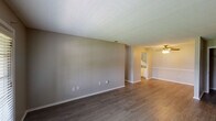 This single-story, 2-bedroom, 1-bathroom home in Long Beach, Mississippi offers a straightforward and functional layout designed for comfortable everyday living. The main living area is open and well-proportioned, featuring durable wood-look laminate flooring, neutral-toned walls, and a textured ceiling. A set of French doors floods the space with natural light and provides access to the exterior. The living area flows into a dining space equipped with a ceiling fan and light fixture, which connects directly to the kitchen. The kitchen features light-toned cabinetry, speckled countertops, a stainless steel sink, and includes a refrigerator, with access to additional storage or utility space through an interior door. Both bedrooms are comfortably sized; one features plush carpeting, a ceiling fan, and a window with blinds, creating a cozy retreat. The bathroom offers a clean, updated vanity with ample drawer storage, a large mirror, and bright overhead lighting. Throughout the home, consistent wood-look flooring, white trim, and a neutral color palette create a cohesive and move-in ready atmosphere suited for a variety of living arrangements.