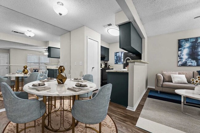 Open-plan dining area with marble round table, blue chairs, gold accents, kitchen beyond, and living room with sofa - Walnut Creek