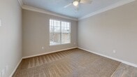 Located at 1932 Stanton Rd in East Point, GA, this single-story 2-bedroom, 2-bathroom home offers a functional and comfortable layout. The entrance opens into hallways finished with warm wood-look flooring and clean neutral-toned walls, guiding residents through the space seamlessly. The combined dining, kitchen, and living area serves as the heart of the home, with the kitchen showcasing white shaker-style cabinetry, light stone countertops, stainless steel appliances including a range and refrigerator, and easy-care hardwood-style flooring. Both bedrooms are carpeted and feature ceiling fans and windows that allow natural light to fill each room. The primary bedroom is generously sized and includes direct access to a dedicated bathroom and a walk-in closet equipped with wire shelving for organized storage. The second bedroom also benefits from natural light and crown molding accents. Each bathroom is fitted with a tub-shower combo and hardwood-style flooring. Additional highlights include four closets for ample storage, a utility room, and an in-unit laundry area. The home's consistent neutral palette and practical finishes throughout create a cohesive, move-in ready atmosphere.