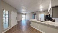 This single-floor residence offers a thoughtfully designed layout that balances comfort and functionality. The open-concept living and dining area is generously sized, featuring neutral-toned carpet, a textured ceiling, and a ceiling fan with light fixture. Multiple windows dressed with white horizontal blinds invite abundant natural light, creating a bright and airy atmosphere throughout the space.

The kitchen is efficiently arranged with a galley-style configuration and showcases stainless steel appliances, including a refrigerator, electric range, and over-the-range microwave. Grey cabinetry, light quartz countertops, and a white subway tile backsplash lend the kitchen a clean, contemporary aesthetic. Wood-look flooring grounds the space with warmth and durability.

The bedroom is comfortably proportioned, also featuring carpet flooring, a ceiling fan, and a window that brings in natural light. A walk-in closet provides ample storage. The adjacent bathroom is split into two distinct areas: a dedicated vanity space with a wide quartz countertop, grey cabinetry, and a well-lit mirror, alongside a separate wet area housing a tiled tub-shower combination, toilet, and additional storage. The space also features a private entry door, contributing to a sense of seclusion and ease of access.