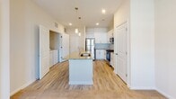 Located at 5895 Arbor Isle Way in Myrtle Beach, South Carolina, this single-floor residence offers a well-designed, open-concept layout with modern finishes throughout. The kitchen serves as a central hub of the home, featuring crisp white shaker cabinetry, granite countertops, a large center island with an undermount sink, and a full suite of stainless steel appliances including a refrigerator, range, and microwave. Light wood-style flooring runs through the kitchen and living areas, lending a clean, cohesive aesthetic. Pendant lighting above the island and recessed ceiling lights add both function and style to the space. The living area is bright and open, anchored by a ceiling fan and French doors that invite natural light and provide access to the outdoors. The bedroom is generously sized with plush carpeting, a ceiling fan, and a large window that fills the room with daylight. The bathroom is well-appointed with granite countertops, white cabinetry, wood-style flooring, and access to a walk-in closet. An in-unit laundry area is conveniently situated nearby. The overall ambiance is fresh, clean, and move-in ready, reflecting a contemporary coastal sensibility suited to the Myrtle Beach lifestyle.