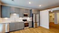 Located at 721 Halifax St in Raleigh, NC, this single-floor unit offers a thoughtfully designed open-concept layout that seamlessly connects the living area and kitchen. Warm hardwood-style flooring flows consistently throughout the space, complementing the clean, neutral color palette on the walls and ceilings.

The kitchen is a standout feature, outfitted with grey shaker-style cabinetry extending to the ceiling for ample storage, white subway tile backsplash, light quartz countertops, and a full suite of stainless steel appliances including a refrigerator, electric range, over-the-range microwave, and dishwasher. Recessed lighting illuminates the kitchen efficiently, while a window with blinds allows natural light into the adjacent dining area.

The living and sleeping areas are bright and open, benefiting from large windows dressed with horizontal blinds that invite natural light while maintaining privacy. Recessed ceiling lights provide consistent illumination throughout.

The bathroom is finished to a contemporary standard, featuring grey shaker-style cabinetry with a white countertop vanity, a backlit LED mirror, tiled flooring in a neutral tone, and a tiled shower area. The overall design is cohesive, modern, and move-in ready, reflecting a clean and functional aesthetic well-suited for urban living in Raleigh.