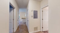 This single-floor residence offers a thoughtfully designed layout that balances comfort and functionality throughout. The kitchen serves as a standout feature, showcasing granite countertops, crisp white cabinetry, and a full suite of stainless steel appliances including a range, microwave, dishwasher, and refrigerator, all set atop warm wood-look flooring. A hallway with multiple doorways and a centrally located electrical panel connects the living spaces efficiently, with a thermostat and floor vents indicating a well-equipped HVAC system. The dining area is bright and welcoming, highlighted by an elegant chandelier, crown molding, natural light from windows with blinds, and direct access to an exterior door. The bedrooms are carpeted and generously sized, with large windows that invite natural light and offer views of surrounding greenery. Crown molding adds a refined touch to the primary bedroom. The unit includes two full bathrooms, each featuring a tub-shower combination, wood-look flooring, and granite vanity tops, as well as a convenient half bath with a pedestal sink and decorative mirror. Neutral warm tones throughout the space create a clean, move-in-ready atmosphere.