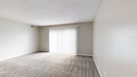Located at 5235 SW 20th Terr in Topeka, Kansas, this single-floor, two-bedroom unit offers a practical and efficiently organized layout. The living room serves as the central gathering space, finished with neutral-toned carpet and a large sliding glass door fitted with vertical blinds, allowing natural light to fill the room while providing access to an outdoor area. The textured ceiling and warm wall tones carry throughout the space, lending a cohesive, understated aesthetic.

The kitchen is equipped with warm oak cabinetry extending to the ceiling for generous storage, black appliances including a refrigerator, range, and dishwasher, and light tile flooring that continues into the adjoining dining area. A ceiling fan with a light fixture overhead adds both functionality and air circulation to this space.

Both bedrooms are carpeted and feature windows with horizontal blinds that admit natural light. The primary bedroom offers a comfortable footprint, while the second bedroom is similarly appointed. Each bedroom benefits from dedicated closet access, contributing to the unit's practical storage capacity. A hallway connects the rooms, completing a straightforward and functional floor plan.