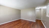 Located on E Oxford Circle in Wichita, Kansas, this single-floor, one-bedroom, one-bathroom unit offers a practical and well-organized layout across a compact but efficiently utilized footprint. The space is finished with neutral taupe-toned walls throughout, creating a consistent and calming aesthetic from room to room.

The spacious bedroom features plush wall-to-wall carpeting that adds warmth underfoot, along with a window fitted with blinds that allows natural light to filter in while maintaining privacy. A dedicated closet provides convenient storage directly off the bedroom.

The common living area showcases rich, warm-toned hardwood-style flooring, offering a durable and visually appealing contrast to the carpeted bedroom. The open wall space and multiple electrical outlets throughout provide flexibility for furniture arrangement.

The bathroom is clean and functional, equipped with a full-sized tub and shower combination featuring white surround panels and chrome fixtures, a toilet, and a vanity. The hardwood-style flooring continues into the bathroom, tying the space together cohesively.

A utility room rounds out the layout, adding practical functionality for storage or laundry needs. Overall, this unit offers a straightforward, move-in-ready design with consistent finishes throughout, well-suited for those seeking a manageable, low-maintenance living space in Wichita.