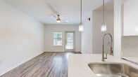 Located at 12100 W 136th St in Overland Park, Kansas, this single-floor unit presents a clean, modern aesthetic throughout. The open-concept living and kitchen area is anchored by wood-look luxury vinyl plank flooring, a ceiling fan, and multiple windows that allow natural light to fill the space. A private entry door adds convenience and accessibility directly from the living area.

The kitchen is well-appointed with white shaker-style cabinetry, quartz countertops, a subway tile backsplash, stainless steel appliances including a refrigerator, electric range, and dishwasher, and a undermount sink. Pendant lighting over the kitchen peninsula adds a stylish finishing touch.

The bedrooms are carpeted for comfort, each featuring ceiling fans and windows with natural views. A dedicated utility area houses a full-size side-by-side washer and dryer along with additional white cabinetry and countertop workspace.

The bathroom is finished with white tile surrounding a soaking tub and shower combination, a white vanity with quartz countertop, brushed nickel fixtures, and a large mirror with overhead lighting. The consistent use of neutral tones and quality finishes creates a cohesive, move-in-ready environment throughout.