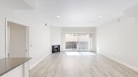 This single-floor residence features 2 bedrooms and 3 bathrooms, thoughtfully designed with a clean, modern aesthetic throughout. Light wood-style flooring runs continuously across the space, complementing the crisp white walls and creating a bright, cohesive atmosphere.

The living room serves as a welcoming centerpiece, featuring a fireplace and a sliding glass door that opens to an outdoor area, filling the room with natural light. A ceiling fan adds comfort to the adjacent bedroom area, which is well-proportioned and bathed in natural light through a large window.

The kitchen is efficiently laid out in a galley style, outfitted with white shaker cabinetry, dark countertops, a subway tile backsplash, and stainless steel appliances including a gas range, refrigerator, and dishwasher. Recessed lighting illuminates the workspace effectively.

The primary bedroom is generously sized and includes mirrored sliding closet doors and a dedicated walk-in closet with multi-level shelving for ample storage. The bathrooms are finished with white vanity cabinetry, dark countertops, and large mirrors with bar lighting. A programmable thermostat is conveniently located in the hallway. The second bedroom is comfortably sized with access to natural light and a panel door entry.