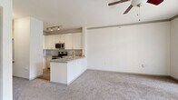 Located at 2450 Oak Hill Cir in Fort Worth, TX, this single-story unit offers a thoughtfully designed layout that maximizes comfort and functionality. The open-concept living area features plush wall-to-wall carpeting, a ceiling fan with light fixture, and track lighting, creating a bright and welcoming atmosphere. A peninsula-style kitchen anchors the space, outfitted with white cabinetry, granite-look countertops, stainless steel appliances including a refrigerator, microwave, and range, and a built-in sink — ideal for both everyday cooking and entertaining. Crown molding accents the living area, adding a refined architectural touch. Sliding glass doors lead to a private balcony, filling the space with natural light and providing outdoor views of the surrounding landscape. The generously sized bedroom is carpeted and includes a ceiling fan, large windows with blinds for privacy and light control, and direct access to both a walk-in closet with built-in shelving and an en-suite bathroom featuring wood-look flooring, a vanity, and standard fixtures. A separate closet in the living area offers additional storage. The unit's clean, neutral palette and functional design make it a comfortable and practical living space.