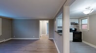 Located on Chatsworth Avenue in Buffalo, NY, this single-floor 2-bedroom, 1-bathroom unit offers a thoughtfully designed layout with consistent, modern finishes throughout. Light wood laminate flooring and neutral gray walls flow seamlessly through every room, complemented by crisp white crown molding that adds a refined architectural detail to the space.

The combined living and dining area provides an open, versatile space with direct sightlines to the kitchen, which features white shaker-style cabinetry, dark granite countertops, black appliances including an electric range and refrigerator, and a window that brings in natural light. A built-in shelving nook adds a charming, functional touch.

The spacious primary bedroom is well-lit with dual windows offering outdoor views, while the second bedroom also features windows with natural light and baseboard heating. Both rooms provide ample space and include closets, with four closets total across the unit.

The bathroom is tiled with large-format stone-look tile, featuring a walk-in shower, a vanity, and a frosted window for privacy and ventilation. A connecting hallway links the main living areas to the bedrooms and bathroom efficiently. Overall, the unit presents a clean, updated aesthetic with practical amenities suited for comfortable everyday living.