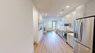Located at 700 Henley St in downtown Knoxville, Tennessee, this thoughtfully designed single-floor residence offers a clean, modern aesthetic with an open and airy feel. Light wood-style flooring runs throughout the main living areas, complemented by crisp white walls and recessed lighting that create a bright, welcoming atmosphere.

The kitchen is a standout feature, showcasing gray shaker-style cabinetry with gold hardware, a textured white tile backsplash, quartz countertops, and a full suite of stainless steel appliances including a French door refrigerator, electric range, and built-in microwave. The open layout connects the kitchen seamlessly to the living area, which benefits from natural light streaming through a glass door that leads to a private balcony with urban views.

The bedrooms are well-proportioned and carpeted, each equipped with a ceiling fan and windows that invite natural light. The primary bedroom offers views of the surrounding urban landscape. The bathroom is thoughtfully outfitted with accessibility features including grab bars, a clean white vanity with gold hardware, and tile flooring. The entryway provides a practical transition into the home, with wall art adding a personalized touch. This residence combines modern design with functional, comfortable living in a prime Knoxville location.