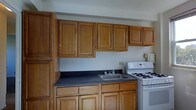 Located at 3300 Fairmount Avenue in Atlantic City, New Jersey, this single-floor space offers a straightforward and functional layout designed for comfortable everyday living. The kitchen is a standout area, showcasing warm honey-toned wood cabinetry that extends both above and below the countertops, providing generous storage throughout. The dark speckled countertops offer a practical contrast to the rich wood tones and provide ample prep space. A stainless steel sink is centered along the counter run, accompanied by standard fixtures. A white gas range sits adjacent to the counter, completing the cooking area with all essential appliances in place. The upper cabinets reach toward the ceiling, maximizing vertical storage and giving the kitchen an organized, well-equipped feel. The neutral wall tones keep the space feeling open and clean, allowing the wood cabinetry to serve as the defining visual element. Overall, the space presents a practical and classic interior that suits a variety of needs, situated in a residential neighborhood of Atlantic City, a city known for its vibrant character along the Jersey Shore.