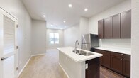 Located in Conroe, TX, this single-story, one-bedroom, one-bathroom home offers a thoughtfully designed layout with modern finishes throughout. The open-concept kitchen is a standout feature, showcasing rich dark-brown shaker-style cabinetry, crisp white countertops, and a full suite of stainless steel appliances including a refrigerator, microwave, and range. A peninsula with a built-in sink provides additional prep space and creates a seamless connection to the living area, which is finished with plush neutral carpeting and recessed lighting. Natural light filters through a window at the far end of the living space, enhancing the bright and airy atmosphere. Dark hardwood-style flooring in the kitchen and bathroom adds a warm contrast to the light-toned walls found throughout the home. The bedroom is a comfortable retreat, carpeted and bathed in natural light from a large window, with a ceiling fan and direct access to both the bathroom and a dedicated walk-in closet. The walk-in closet features built-in shelving and hanging rods, offering practical and well-organized storage. The bathroom is finished with a dark-cabinetry vanity, white countertop, and a framed mirror with overhead lighting, maintaining the consistent design language found throughout the home.