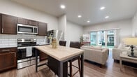 Located at 802 US-54 W in Andover, Kansas, this thoughtfully designed one-bedroom, one-bathroom residence offers a efficient and comfortable single-floor layout. The open-concept living and kitchen area serves as the heart of the home, where warm wood-look flooring flows seamlessly throughout. The kitchen is well-equipped with rich dark cabinetry, granite countertops, a classic white subway tile backsplash, and stainless steel appliances including a range, microwave, and refrigerator. A freestanding island with a butcher block top provides additional prep space and casual seating. The living room is bright and welcoming, anchored by large sliding glass doors that flood the space with natural light and provide direct access to an outdoor patio with courtyard views. The bedroom offers a generous footprint, featuring a ceiling fan, a broad window with outdoor views, and wood-look flooring. A hallway connects to the full bathroom, which is finished with a wide granite-topped vanity, dark wood cabinetry, and a full-length mirror. A closet and in-unit laundry area add to the practicality of this well-rounded residence, making it an efficient and attractive living space.