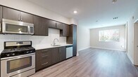 Located in the heart of Los Angeles' vibrant Little Tokyo neighborhood, this well-designed one-bedroom, one-bathroom unit offers a thoughtful layout across a single floor. The open-concept living and kitchen area sets a modern tone, featuring light wood-style flooring that flows throughout the main spaces and creates a clean, cohesive aesthetic.

The kitchen is a standout feature, equipped with sleek dark-wood cabinetry that extends to the ceiling for ample storage, a crisp white subway tile backsplash, white quartz-style countertops, and a full suite of stainless steel appliances including a gas range, built-in microwave, dishwasher, and refrigerator. The living area is bright and open, benefiting from natural light streaming in through a window with outdoor views.

The bedroom is a comfortable, carpeted retreat with soft neutral tones, a window with views of the surrounding area, and a dedicated closet for storage. A hallway connects the bedroom to the full bathroom, which includes a tub-shower combination, a wall-mounted storage cabinet with dark wood finish, and clean white tile surround. Throughout the unit, white baseboards, neutral walls, and consistent finishes contribute to a modern and move-in ready ambiance.