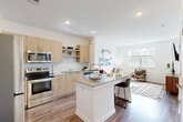 Located at 15141 Mattawoman Dr in Brandywine, MD, this thoughtfully designed one-bedroom, one-bathroom residence offers a modern and functional living experience across a single floor. The open-concept layout seamlessly connects the kitchen, dining area, and living room, creating a bright and cohesive space ideal for both everyday living and entertaining. The kitchen is outfitted with light wood cabinetry, granite countertops, a subway tile backsplash, and a full suite of stainless steel appliances, including a range, microwave, and refrigerator. A central kitchen island with seating provides additional prep space and a casual dining option. Wood-style flooring flows throughout the entire residence, adding warmth and continuity. The living room benefits from natural light through large windows and offers a comfortable, open atmosphere. The bedroom is a serene retreat with ample natural light, generous closet space, and direct access to the full bathroom. The bathroom features matching light wood vanity cabinetry with granite countertops and a clean, contemporary aesthetic. Additional conveniences include in-unit laundry and three closets for plentiful storage throughout the home.