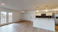 This single-floor residence offers a clean, modern aesthetic defined by light hardwood flooring that flows seamlessly throughout every room. The open-concept living area is generously proportioned, bathed in natural light from a large window, and accented by a ceiling fan overhead. It connects directly to a stylish kitchen, creating an inviting, functional layout ideal for everyday living and entertaining.

The kitchen is a standout feature, showcasing a two-tone design with rich dark lower cabinetry contrasted by crisp white upper cabinets. Light quartz countertops and a slate-blue subway tile backsplash add refined detail, while stainless steel appliances—including a gas range, over-the-range microwave, and refrigerator—provide modern convenience. A peninsula with seating overhang and pendant lighting completes the space.

The bedroom is a peaceful retreat, featuring a ceiling fan, a natural light-filled window, and generous closet storage provided by a wide double sliding-door closet. The full bathroom is well-appointed with a white shaker-style vanity, lighted mirror, and a bright window for natural ventilation. A dedicated laundry area with in-unit washer and dryer adds everyday practicality. Recessed lighting and white walls throughout contribute to the home's clean, contemporary feel.