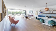 Located at 8740 S La Tijera Blvd in Los Angeles, this single-floor amenity space offers a well-appointed, modern interior designed for both relaxation and social gatherings. The open-plan layout is anchored by wide-plank wood-look flooring that flows seamlessly throughout, lending warmth and visual continuity to the entire space.

The living area is generously sized, featuring recessed lighting, white walls, and large sliding glass doors that open directly onto an outdoor patio. These expansive glazed openings flood the interior with natural light and provide easy indoor-outdoor connectivity, with views of lush greenery beyond the terrace. Decorative wall art adds a curated, contemporary touch, complemented by a mix of seating arrangements including lounge chairs and sofas.

A dedicated recreation zone houses a full-size billiards table alongside an extended sectional sofa, creating a casual entertainment hub. The kitchen area is distinctly styled with bold navy-blue cabinetry, copper-toned hardware, marble-effect countertops, open wood shelving, and stainless steel appliances including a full-size refrigerator and built-in microwave. A dining table with teal upholstered chairs bridges the kitchen and lounge zones, completing this versatile, well-designed communal space.