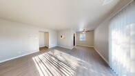 Located at 1182 Quail Run Drive in Columbus, Indiana, this two-bedroom, one-bathroom single-story home offers a thoughtfully organized layout with a clean, neutral aesthetic throughout. The open living room is a welcoming centerpiece, featuring light-toned vinyl plank flooring, a ceiling fan, and a sliding glass door dressed with vertical blinds that invite abundant natural light and outdoor views. The galley-style kitchen is efficiently designed with warm wood cabinetry, granite-look countertops, a stainless steel sink, and black appliances including an electric range and dishwasher. A hallway connects the main living areas to the private quarters, where both bedrooms are carpeted for comfort. The spacious primary bedroom benefits from generous natural light through large windows and includes access to a walk-in closet outfitted with wire shelving for ample storage. The second bedroom also features plush carpet, a window for natural light, and a dedicated closet with louvered bifold doors. The full bathroom is finished with white tile surround and a tub-shower combination. Clean white walls, consistent trim work, and a neutral color palette create a cohesive and move-in-ready feel throughout this well-appointed home.