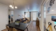 This single-floor residence offers a thoughtfully designed open-concept layout that seamlessly connects the living, dining, and kitchen areas. The living room is a comfortable and inviting space, featuring wood-look flooring, a ceiling fan, large windows with blinds that allow ample natural light, and a private exterior door. A wall-mounted TV and stylish décor complete the room's modern aesthetic.

The kitchen is well-equipped with white shaker-style cabinetry, quartz countertops, stainless steel appliances including a refrigerator, range, microwave, and dishwasher, as well as a peninsula with bar seating — ideal for casual dining. A secondary entry door with a transom window adds both function and charm.

The two bedrooms are generously sized, each featuring wood-look flooring, large windows with natural light, ceiling fans, and ample closet space. The primary bedroom connects to a private en-suite bathroom with a white vanity, large mirror, and a spacious walk-in closet. The secondary bathroom features a sleek, elongated white sink vanity, large mirror, and wood-look flooring.

Throughout the residence, a neutral color palette, clean lines, and consistent modern finishes create a cohesive and welcoming ambiance.