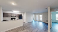 Located at 13135 Masons Bridge Rd in Woodbridge, VA, this 2-bedroom, 2-bathroom residence offers a thoughtfully designed single-level layout. The open-concept living and kitchen area serves as the heart of the home, featuring durable wood-style plank flooring throughout and a bright, neutral color palette. The kitchen is equipped with dark cabinetry, granite-style countertops, black appliances including a refrigerator and range, and a peninsula that opens to the living area — ideal for both cooking and entertaining. The living room is generously sized and benefits from abundant natural light, with a set of glass double doors leading to an outdoor entrance. Both bedrooms are well-proportioned, each with large windows that invite natural light and views of the surrounding area. The primary bedroom connects to a full bathroom and a dedicated walk-in closet with built-in shelving. A second closet provides additional storage. Each bathroom features a soaking tub and shower combination, granite-topped vanity, and wood-style flooring. The clean, modern finishes and functional layout make this a practical and comfortable Woodbridge residence.