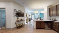Located at 8320 University Executive Park Dr in Charlotte, NC, this single-floor residence offers a thoughtfully designed open-concept layout that seamlessly connects the kitchen, dining, and living areas. Light hardwood-style flooring runs throughout the main living spaces, complementing the bright, white walls and creating a warm, cohesive aesthetic.

The kitchen is well-appointed with rich dark-stained cabinetry, stainless steel appliances including a French door refrigerator, electric range, and built-in microwave, all set against a classic subway tile backsplash. Light granite countertops extend to a central island with bar seating and pendant lighting overhead, ideal for both meal preparation and casual dining.

The living area is bathed in natural light from large windows with blinds, creating an inviting atmosphere. A ceiling fan adds comfort, while access to an outdoor area brings additional natural light into the space.

The bedroom is a serene retreat featuring plush carpeting, ample natural light, and generous space for a full furniture arrangement. The bathroom is finished with large-format tile flooring, a granite-topped vanity with dark cabinetry, and a clean, neutral palette throughout. In-unit laundry is also available, adding everyday convenience to this well-rounded residence.