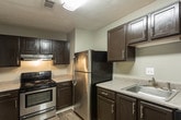 Located at 400 Winchester Trl in Smyrna, GA, this single-floor unit offers a practical and well-organized layout designed for comfortable everyday living. The entryway opens into a spacious living area finished with plush wall-to-wall carpeting and neutral gray walls, creating a clean and versatile backdrop. A sliding glass door with vertical blinds allows natural light to fill the space while providing access to the outdoors. The kitchen is a standout feature, showcasing dark espresso cabinetry, stainless steel appliances including a refrigerator and electric range, speckled laminate countertops, and wood-look luxury vinyl plank flooring that adds warmth and durability. Multiple bedrooms are spread throughout the unit, each carpeted and painted in soft neutral tones. The rooms benefit from natural light through window blinds and offer ample wall space for flexible furniture arrangements. Two full bathrooms serve the unit, one featuring white subway tile surrounding a soaking tub and the other with wood-look vinyl plank flooring, a tub-shower combo, and a vanity with countertop space. Throughout the unit, consistent neutral finishes and clean white trim work together to create a cohesive, move-in-ready aesthetic.