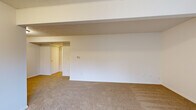 Located at 4568 Blackstone Trail in Okemos, Michigan, this single-floor unit offers a straightforward and functional layout designed for comfortable everyday living. Throughout the living areas, warm beige wall-to-wall carpeting creates a cohesive and inviting atmosphere, while textured ceilings add a classic architectural detail.

The main living space is open and generously sized, featuring structural beams that define distinct zones within the room. A vertical-blind window allows natural light to filter in, and a front entry door provides direct access. The space flows naturally into additional rooms, connected by a central hallway.

The galley-style kitchen is well-appointed with warm wood-toned cabinetry lining both sides, offering ample storage above and below the countertops. Light-toned counters, a stainless steel refrigerator, an electric range, and a dishwasher are all included. Tile-style flooring provides a durable, easy-to-clean surface in this area.

The bedroom is notably spacious and features dual sets of bifold closet doors, providing generous storage capacity with separate hanging rods and shelving. A utility closet nearby houses additional mechanical systems. A secondary carpeted room with a small window and access to a utility area adds further flexibility to the floor plan. The overall aesthetic throughout is clean, neutral, and move-in ready.
