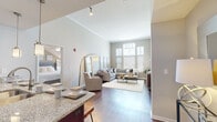 Located at 3351 SW Kessler Dr in Lee's Summit, MO, this single-floor residence offers a thoughtfully designed open-concept layout with impressive soaring ceilings and rich hardwood-style flooring throughout the main living areas. The expansive living room is bathed in natural light through oversized windows, creating an airy, welcoming atmosphere. The gourmet kitchen is a standout feature, showcasing rich dark cabinetry, granite countertops, stainless steel appliances, a built-in wine rack, pendant and track lighting, and a breakfast bar with seating — ideal for both casual dining and entertaining. The bedroom features a distinctive tray ceiling with a ceiling fan, plush carpeting, large windows with outdoor views, and generous closet space, including a spacious walk-in closet with wire shelving. The bathrooms are finished with granite countertops, rich wood cabinetry, and large mirrors, with one offering a soaking tub and another a glass-enclosed shower. The neutral, warm color palette and carefully considered finishes throughout contribute to a cohesive and refined ambiance, making this a comfortable and well-appointed residence in Lee's Summit.
