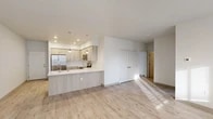 Located at 15922 E Valleyway Ave in Spokane, Washington, this single-floor residence offers a clean, modern aesthetic with thoughtfully designed living spaces. The open-concept layout connects the living area to a well-appointed kitchen, which features light wood-tone cabinetry extending to the ceiling, a crisp white quartz peninsula countertop with an undermount sink, and a full suite of stainless steel appliances including a refrigerator, electric range, microwave, and dishwasher. Pendant lighting above the peninsula adds a refined touch. Light wood-look flooring flows throughout the main living spaces, lending warmth and continuity to the interior. The living area benefits from natural light streaming through windows fitted with horizontal blinds, and a private exterior door provides convenient outdoor access. The bedrooms are carpeted for comfort, each featuring windows that invite natural light and views of the surrounding neighborhood. Two bathrooms mirror each other in design, each offering a tub-shower combination with a curved curtain rod, light wood-look tile flooring, and light-toned quartz countertops. The overall palette of soft whites and warm neutrals creates a bright, airy ambiance throughout the residence.