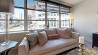 Located at 113–175 Trumbull Street in the heart of Hartford, CT, this single-floor studio is designed with a contemporary aesthetic that balances functionality and style. The open-concept layout seamlessly integrates the living, sleeping, and kitchen areas into one cohesive, light-filled space.

The kitchen is a standout feature, showcasing floor-to-ceiling matte cabinetry in a soft grey tone with black hardware, dark granite countertops, and a decorative patterned tile backsplash. Stainless steel appliances, including a built-in microwave and freestanding range, complete this well-appointed cooking space. Light hardwood flooring flows throughout, lending warmth to the modern design.

The main living area is generously proportioned, accommodating a full sleeping area alongside a comfortable lounge space. Large floor-to-ceiling windows frame expansive views of Hartford's downtown skyline, filling the space with abundant natural light.

The bathroom is finished with large-format stone-look floor tiles, patterned accent wall tiles that echo the kitchen backsplash, a frameless glass shower, and a sleek floating vanity, creating a cohesive and polished aesthetic throughout the entire studio.