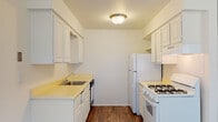 This single-floor unit offers a functional and straightforward layout with clearly defined living spaces. The galley-style kitchen is well-equipped, featuring white cabinetry along both walls, light-toned countertops, a stainless steel sink, a gas range, a dishwasher, and a full-size refrigerator. Wood-look flooring runs throughout the kitchen, providing a clean contrast to the white cabinetry.

The living area is generously proportioned, with plush carpeting, neutral walls, and a ceiling fan that contributes to a comfortable atmosphere. A large window fitted with vertical blinds allows natural light to fill the space, while a front entry door connects directly to this area. An additional open room extends from the living space, offering flexible use as a dining area or secondary lounge.

The bedroom is carpeted and includes a built-in closet with bifold doors and a ceiling fan. Its neutral tones create a calm, restful environment with easy access to the hallway.

The bathroom is finished in light, neutral tones with tile flooring, a single-sink vanity with white cabinetry, a wall-mounted mirror, a toilet, and a tub-shower combination. The overall design of the unit prioritizes practicality and ease of living.