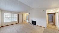 Located at 619 Park Hill Dr in Fairlawn, Ohio, this well-appointed two-bedroom, two-bathroom single-floor home offers a comfortable and functional layout. The open living room is a standout, featuring vaulted ceilings, plush carpeting, a classic fireplace, and a large window that allows natural light to fill the space. The kitchen connects seamlessly to the living area via a pass-through counter and is equipped with white cabinetry, dark hardwood-style flooring, black appliances including an electric range and built-in microwave, track lighting, and granite-style countertops. A hallway leads from the main living area to the two bedrooms and bathrooms. The generously sized primary bedroom boasts vaulted ceilings and access to a spacious walk-in closet with wire shelving. The bathrooms feature hardwood-style flooring, granite-style vanity tops, and tub-shower combinations. The second bedroom also offers carpeted flooring and ample space. Throughout the home, warm wood-tone door frames and trim provide a cohesive design touch. Textured ceilings and neutral wall tones create a clean, versatile aesthetic ready for personalization.