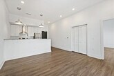 This well-appointed 1-bedroom, 2-bathroom residence offers a clean, modern aesthetic with a thoughtfully designed open-concept layout. Light wood-tone flooring flows consistently throughout, complementing the crisp white walls and creating a bright, airy atmosphere.

The kitchen serves as a central focal point, showcasing granite countertops, white shaker-style cabinetry, a white subway tile backsplash, and a full suite of stainless steel appliances including a refrigerator, range, and dishwasher. A peninsula with pendant lighting above provides additional prep space and serves as a natural divide between the kitchen and the living area.

The living area is generously proportioned, featuring a ceiling fan and a sliding glass door that invites natural light and offers outdoor views. The bedroom is comfortably sized with vaulted ceilings, a ceiling fan, and multiple windows that frame exterior views, creating a bright and open feel. A dedicated closet provides practical storage.

Both bathrooms are finished with consistent materials — granite vanity countertops, white subway tile, and light tile flooring. One bathroom features a full soaking tub with a shower combination, while the second bathroom connects conveniently to the bedroom, offering added functionality and privacy.