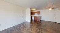 This single-floor residence offers a thoughtfully laid-out living environment with a cohesive blend of materials and finishes throughout. The open living area is spacious and filled with natural light streaming through a large sliding glass door dressed with vertical blinds, complemented by dark hardwood-style flooring that extends through the main living and kitchen spaces.

The kitchen is well-equipped with warm-toned wood cabinetry, granite-look countertops, and a full suite of white appliances including a refrigerator, electric range, microwave, and dishwasher. A peninsula provides additional counter space and convenient access to the adjoining living area.

The bedrooms feature plush carpeting and windows fitted with blinds that allow for ample natural light and privacy. The layout accommodates multiple sleeping or flexible-use rooms, each offering a clean, neutral palette.

The bathroom includes a rich wood vanity with granite-look countertops, a large wall mirror, a stylish multi-bulb light fixture, and dark hardwood-style flooring. A separate tub-shower combo with a grab bar provides added functionality and accessibility.

A dedicated in-unit laundry area houses a full-size washer and dryer with wire shelving above for storage. The space is presented in move-in-ready condition, combining practicality with comfortable, well-maintained living spaces throughout.