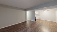 Located at Lamplight Lane SE in Kentwood, Michigan, this single-floor unit offers a well-organized layout with a cohesive, neutral design palette throughout. The galley-style kitchen is outfitted with white raised-panel cabinetry, granite-look countertops, dark hardwood-style vinyl flooring, and stainless steel appliances including a refrigerator, electric range, and dishwasher. A double-basin stainless steel sink with a modern faucet adds practicality, while under-cabinet lighting enhances the workspace. The open living and dining area features the same rich dark hardwood-style flooring, neutral gray walls, and clean white trim. A sliding glass door with vertical blinds fills the living space with natural light and provides direct access to an outdoor area. The adjacent dining space flows seamlessly into the kitchen through an open pass-through. The bedroom is finished with plush wall-to-wall carpeting, soft gray walls, a textured ceiling, and a window with horizontal blinds that admits natural light. The full bathroom includes a white vanity with granite-look countertop, a large mirror, and a full-size tub and shower combination with clean white surround. Hardwood-style flooring carries through the bathroom, maintaining design consistency throughout the unit.