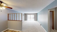 Located at 3641 Lancaster Ln N in Plymouth, Minnesota, this single-floor residence offers a functional and straightforward layout with a blend of updated finishes and classic design elements. The living area is generously sized, featuring soft wall-to-wall carpeting, neutral gray walls, and a textured ceiling. A sliding glass door floods the space with natural light and opens to a private balcony overlooking the exterior brick facade. Baseboard heating runs along the perimeter walls, and a wall-mounted air conditioning unit provides climate control. A wooden half-wall divider partially separates the entry area from the living space, adding a subtle architectural detail.

The kitchen has been updated with white cabinetry, granite-look countertops, stainless steel appliances including a refrigerator and range, and durable wood-look vinyl plank flooring. A raised breakfast bar with a wood-trimmed partition connects the kitchen to the dining and living areas. Bedroom spaces are carpeted and feature sliding closets with built-in shelving. Windows provide outdoor views and natural light. The bathroom is finished with tile flooring, a full tub-shower surround, and a vanity with granite-look countertops.