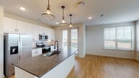 Located at 2878–2898 Spencer Rd in Denton, TX, this well-appointed single-story residence offers a thoughtfully designed layout with modern finishes throughout. The open-concept kitchen serves as the heart of the home, showcasing dark granite countertops, crisp white shaker cabinetry, a classic subway tile backsplash, and a full suite of stainless steel appliances including a refrigerator, electric range, and over-the-range microwave. A large kitchen island with pendant lighting provides additional workspace and anchors the space. The living area features warm wood-look flooring and multiple windows that invite generous natural light and outdoor views. A dedicated hallway connects the private quarters, where the bedroom is finished with plush carpeting, a ceiling fan, and a sizable window overlooking greenery. The primary bathroom is designed for comfort, featuring a walk-in glass shower with white tile surround, a single-sink vanity with granite countertops, and wood-look flooring. A second full bathroom mirrors the same refined aesthetic with a tiled soaking tub and shower combo. Additional highlights include a spacious walk-in closet with multi-level shelving and a dedicated in-unit laundry room equipped with a full-size washer and dryer.