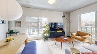 Located in Edmonton's vibrant 124th Street neighbourhood, this thoughtfully designed 2-bedroom, 2-bathroom unit offers a contemporary living experience across a single, well-organized floor. The open living and dining area is a standout space, characterized by striking exposed concrete ceilings, light hardwood flooring, and large windows that frame views of the surrounding streetscape, flooding the interior with natural light. A pendant globe light anchors the dining area, while the living room benefits from an additional concrete column detail that adds an industrial-modern aesthetic.

Both bedrooms are bright and well-proportioned, each with access to natural light via generously sized windows with outdoor views. The primary bedroom features a large window overlooking mature trees, while the secondary bedroom connects seamlessly to an adjacent flex room currently used as an office, complete with built-in closet space. Each bedroom is paired with its own dedicated bathroom, both finished with clean white countertops, warm wood-tone vanity cabinetry, built-in shelving, and glass-enclosed showers. The hallway connects all spaces efficiently, and the two closets provide practical storage throughout.