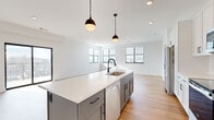 Located in Merriam, Kansas, this contemporary 2-bedroom, 2-bathroom residence offers a thoughtfully designed single-level floor plan with modern finishes throughout. Light wood-tone flooring flows seamlessly across the entire space, complementing the bright, white walls and creating a clean, cohesive aesthetic.

The open-concept kitchen and living area serves as the heart of the home. The kitchen is outfitted with white shaker cabinetry, a white subway tile backsplash, stainless steel appliances, and a large central island with a crisp white quartz countertop, a built-in sink with a matte black faucet, and stylish pendant lighting overhead. The adjacent living area is bathed in natural light from multiple windows and features sliding glass doors that open to a private balcony with outdoor views.

The primary bedroom is generously proportioned and includes access to a dedicated closet. Its ensuite bathroom is elegantly appointed with a dual-sink vanity featuring white cabinetry and quartz countertops, matte black hardware, illuminated mirrors, and a glass-enclosed shower. The second bedroom is well-sized with a ceiling fan and a window providing natural light. Three closets total offer ample storage throughout. A dedicated in-unit laundry room with a full-size washer and dryer completes this well-appointed residence.