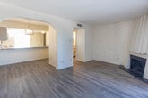 Located at 299 Kingspoint Dr in El Paso, Texas, this two-story home is defined by a distinctive architectural character rooted in its painted white brick walls, which appear consistently throughout the interior and lend a cohesive, textural charm to every room. The main level features hardwood-style flooring that flows through the entry hallway, living areas, and kitchen. The hallway connects key living spaces and is illuminated by wall-mounted lighting, with a staircase featuring a sleek black metal railing leading to the upper floor. The living room is a standout space, offering a wood-burning fireplace framed by the signature brick walls and a large sliding glass door with vertical blinds that fills the room with natural light. An arched doorway leads to the kitchen, which is equipped with granite-style countertops, white cabinetry with modern hardware, a full appliance suite including an electric range, over-the-range microwave, and a pendant-lit sink area. The bedrooms are located upstairs and feature plush carpet, painted brick accent walls, ceiling fans with light fixtures, and windows with blinds for natural light. The bathroom includes a full tub-shower combination with white tile surround and granite-topped vanity. Textured ceilings are present throughout the home.