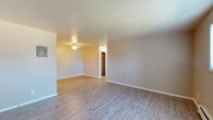 Located at 7240 Tennyson St in Westminster, Colorado, this single-floor unit offers a practical and comfortable layout across several well-defined living areas. The living space is generously sized, featuring light wood-style plank flooring that flows throughout the main areas, neutral-toned walls, and a textured ceiling. A ceiling fan light fixture adds functionality, while a window with vertical blinds allows natural light to fill the room. The entry area leads seamlessly into the open living space, providing a welcoming first impression. The kitchen is efficiently designed in a U-shaped configuration, offering warm wood cabinetry with ample upper and lower storage, laminate countertops, and black appliances including a refrigerator, electric range, and dishwasher. Wood-style flooring continues in this space, complementing the cabinetry tones. The bedroom is carpeted for comfort, featuring dual windows that bring in natural light, a ceiling fan, a baseboard heater, and a wall-mounted air conditioning unit for year-round climate control. A closet provides dedicated storage. The bathroom is finished with classic white tile accented by a bold green tile border, enclosing a full bathtub and shower combination, with a small window providing ventilation and light.
