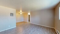 Located at 7240 Tennyson St in Westminster, Colorado, this single-floor unit offers a practical and comfortable layout across several well-defined living areas. The living space is generously sized, featuring light wood-style plank flooring that flows throughout the main areas, neutral-toned walls, and a textured ceiling. A ceiling fan light fixture adds functionality, while a window with vertical blinds allows natural light to fill the room. The entry area leads seamlessly into the open living space, providing a welcoming first impression. The kitchen is efficiently designed in a U-shaped configuration, offering warm wood cabinetry with ample upper and lower storage, laminate countertops, and black appliances including a refrigerator, electric range, and dishwasher. Wood-style flooring continues in this space, complementing the cabinetry tones. The bedroom is carpeted for comfort, featuring dual windows that bring in natural light, a ceiling fan, a baseboard heater, and a wall-mounted air conditioning unit for year-round climate control. A closet provides dedicated storage. The bathroom is finished with classic white tile accented by a bold green tile border, enclosing a full bathtub and shower combination, with a small window providing ventilation and light.