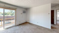 Located on Main Street in Mineral Ridge, Ohio, this 2-bedroom, 1-bathroom unit offers a practical single-floor layout designed for comfortable everyday living. The entrance leads into a carpeted living room featuring baseboard heating, a wall-mounted air conditioning unit, and a sliding glass door that opens to an outdoor balcony, filling the space with natural light and providing outdoor access. The kitchen is equipped with dark wood cabinetry, a double basin sink, a white electric range, a dishwasher, and a white refrigerator, with textured wallpaper accents and tile flooring adding a traditional character to the space. The primary bedroom is a well-sized room featuring carpet flooring, a window overlooking the exterior, decorative wallpaper border trim, and baseboard heating. The second bedroom mirrors a similar layout, with carpet flooring, natural light from a window, and generous closet storage provided by double bifold closet doors. The full bathroom includes a tiled tub-and-shower combination, a toilet, and a vanity. Throughout the unit, textured ceilings, carpet flooring in living areas, and baseboard heating systems are consistent features that define the overall character of this straightforward and functional home.