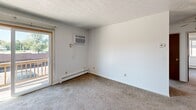 Located on Main Street in Mineral Ridge, Ohio, this 2-bedroom, 1-bathroom unit offers a practical single-floor layout designed for comfortable everyday living. The entrance leads into a carpeted living room featuring baseboard heating, a wall-mounted air conditioning unit, and a sliding glass door that opens to an outdoor balcony, filling the space with natural light and providing outdoor access. The kitchen is equipped with dark wood cabinetry, a double basin sink, a white electric range, a dishwasher, and a white refrigerator, with textured wallpaper accents and tile flooring adding a traditional character to the space. The primary bedroom is a well-sized room featuring carpet flooring, a window overlooking the exterior, decorative wallpaper border trim, and baseboard heating. The second bedroom mirrors a similar layout, with carpet flooring, natural light from a window, and generous closet storage provided by double bifold closet doors. The full bathroom includes a tiled tub-and-shower combination, a toilet, and a vanity. Throughout the unit, textured ceilings, carpet flooring in living areas, and baseboard heating systems are consistent features that define the overall character of this straightforward and functional home.