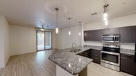 Located at 455 South Recker Road in Gilbert, AZ, this well-appointed single-floor residence offers three bedrooms, two bathrooms, and a thoughtfully designed layout. The open-concept kitchen is a standout feature, showcasing granite countertops, dark espresso cabinetry, stainless steel appliances including a refrigerator, range, and microwave, and stylish pendant lighting. A peninsula with a built-in sink creates a natural gathering point that connects the kitchen to the living area. The living room features light wood-style tile flooring, a ceiling fan, and a sliding glass door that opens to a private patio, filling the space with natural light. The bedrooms are carpeted and each equipped with ceiling fans and window blinds, with the secondary bedrooms offering multiple windows for added brightness. The bathrooms are finished with dark vanity cabinetry, white countertops, and light tile flooring; one features a walk-in shower with glass doors, while the other includes a shower-tub combination. A dedicated laundry room houses a full-size side-by-side washer and dryer with built-in shelving overhead. A hallway and closet complete the functional floor plan of this Gilbert residence.