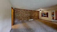Located at 5186-5208 Everhard Rd NW, Unit 12 in Canton, Ohio, this two-bedroom, one-bathroom residence offers a comfortable and functional single-floor layout. The kitchen is a standout feature, boasting warm honey-toned cabinetry, granite-look countertops, a mosaic tile backsplash, stainless steel appliances, and tile flooring — all topped with a ceiling fan. A charming pass-through window with louvered shutters connects the kitchen to the main living area, enhancing the open feel of the home. The spacious living room is distinguished by a striking full-length exposed brick accent wall, carpeted flooring, and a ceiling fan, lending the space a warm, character-filled ambiance. The primary bedroom is generously sized, featuring dual built-in closets with wood panel doors and a ceiling fan. The second bedroom is well-proportioned with its own closet, carpeted floors, a ceiling fan, and a window that lets in natural light. The full bathroom is cleanly appointed with tile flooring, a tub-shower combination, a dark-toned vanity with a white countertop, wall-mounted cabinetry, and a mirror. Baseboard heating is present throughout, and warm wood trim accents the windows and doors across the unit.
